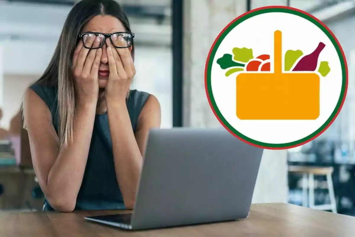 Mujer con gafas frente a una computadora portátil cubriéndose el rostro con las manos, con un ícono de una cesta de compras con alimentos en la esquina superior derecha.