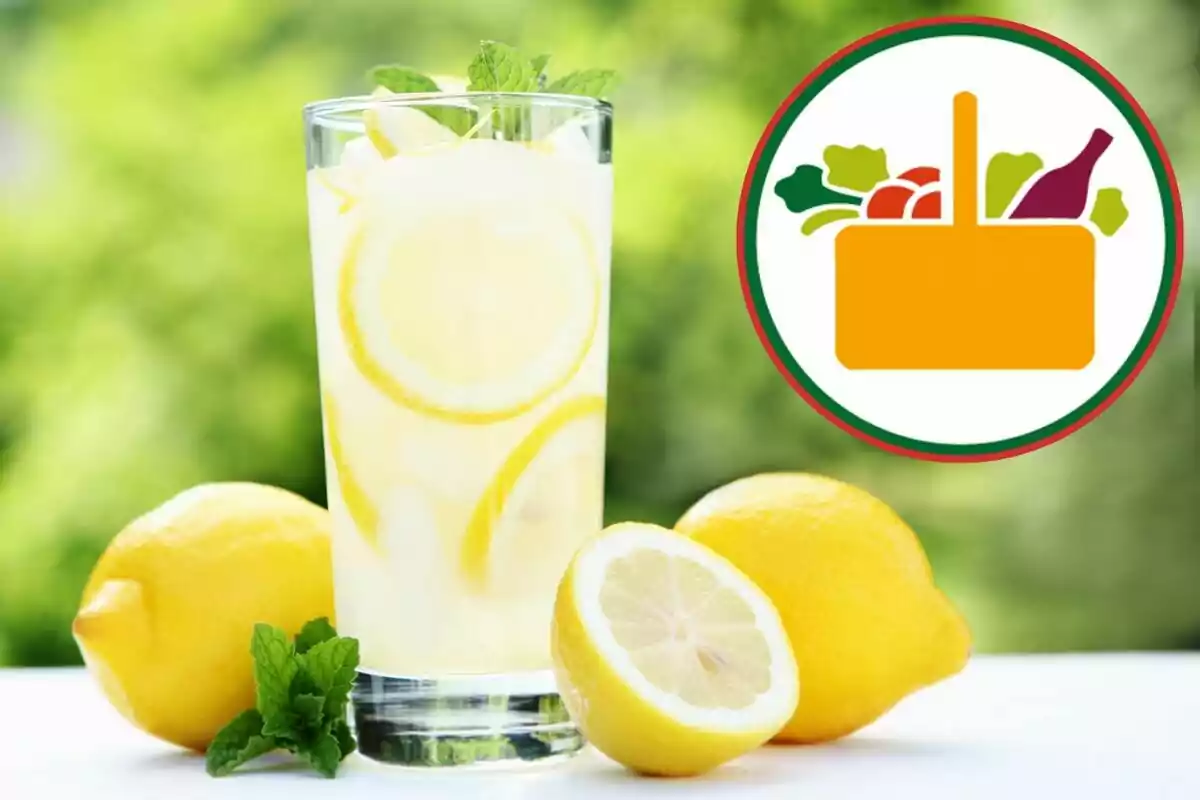 Vaso de limonada con rodajas de limón y hojas de menta junto a limones frescos y un logotipo de canasta de alimentos en el fondo Vaso de limonada con rodajas de limón y hojas de menta junto a limones frescos y un logotipo de canasta de alimentos en el fondo