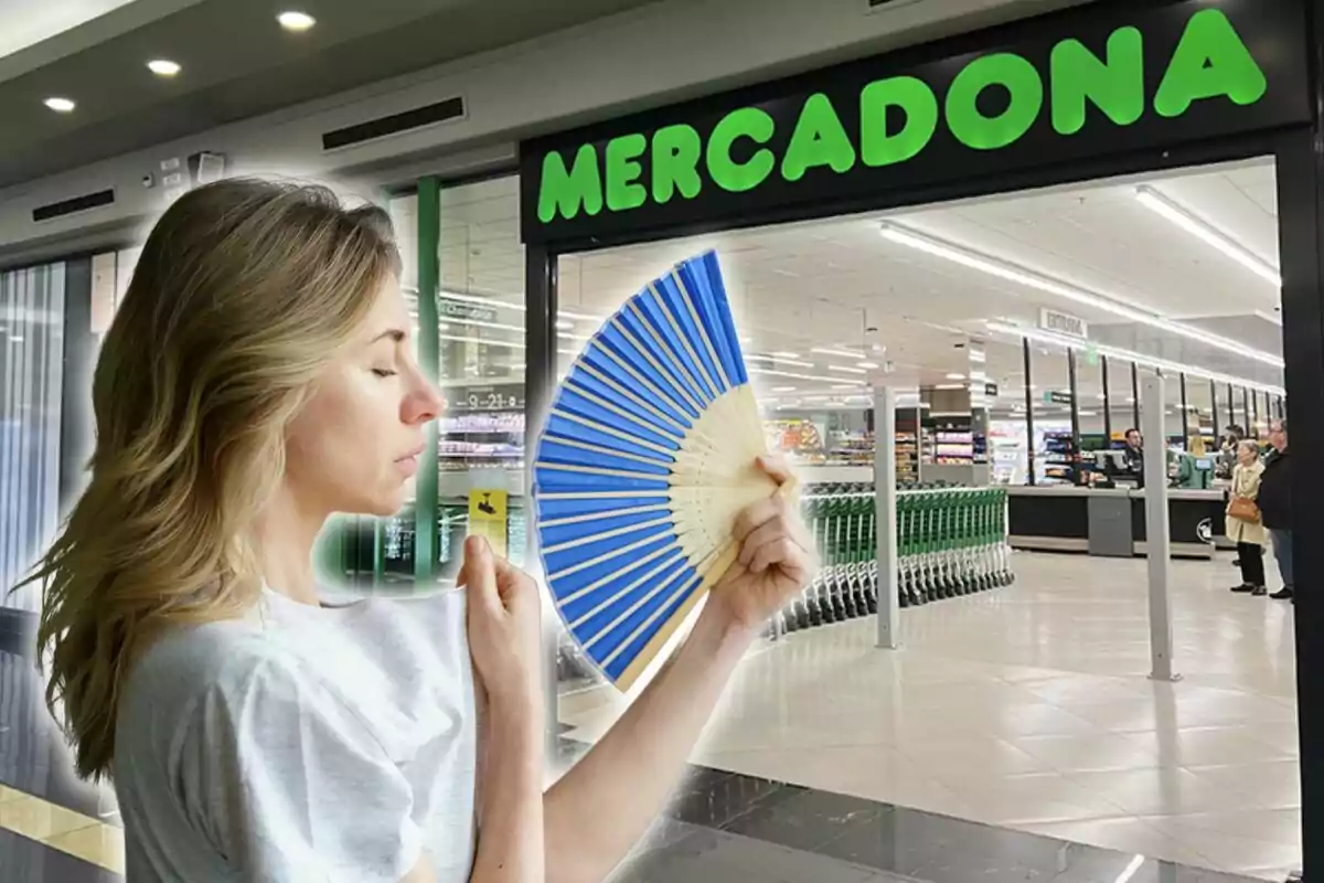 Una mujer con un abanico azul se encuentra frente a la entrada de un supermercado.