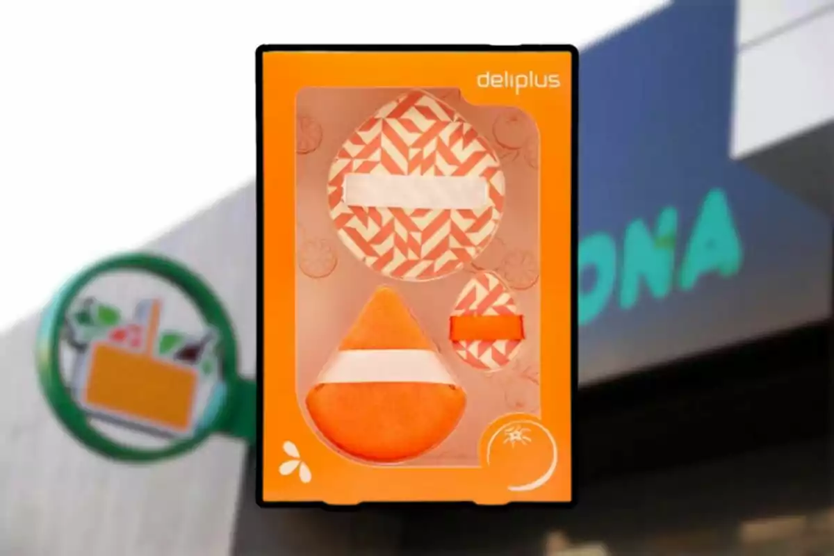 Caja de esponjas de maquillaje Deliplus con diseño geométrico en tonos naranjas frente a un cartel de supermercado. Caja de esponjas de maquillaje Deliplus con diseño geométrico en tonos naranjas frente a un cartel de supermercado.