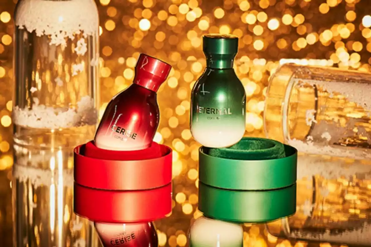 Dos frascos de perfume en tonos rojo y verde sobre una superficie reflectante con un fondo de luces doradas desenfocadas. Dos frascos de perfume en tonos rojo y verde sobre una superficie reflectante con un fondo de luces doradas desenfocadas.