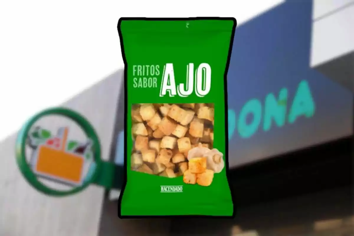 Bolsa verde de fritos sabor ajo de la marca Hacendado frente a una tienda Mercadona desenfocada. Bolsa verde de fritos sabor ajo de la marca Hacendado frente a una tienda Mercadona desenfocada.