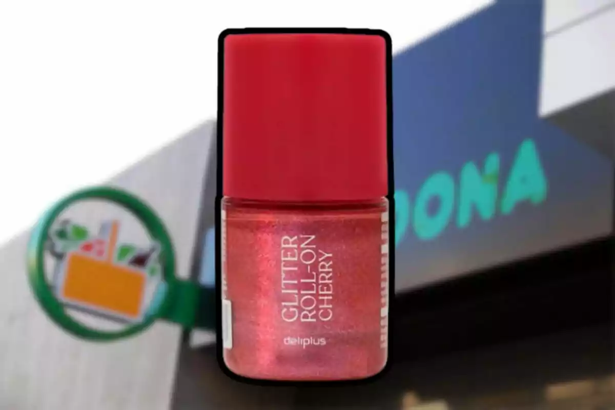 Envase de glitter roll-on color cereza de la marca Deliplus con tapa roja, frente a una tienda Mercadona desenfocada. Envase de glitter roll-on color cereza de la marca Deliplus con tapa roja, frente a una tienda Mercadona desenfocada.