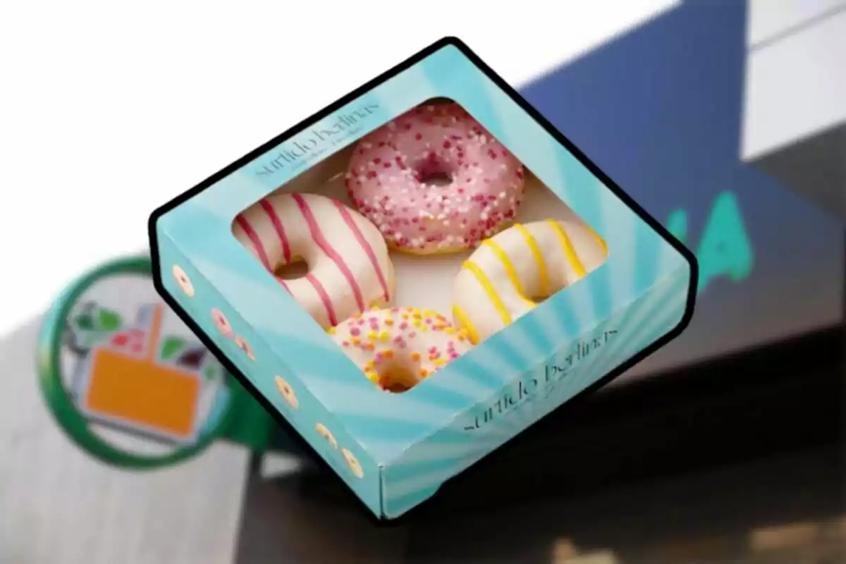 Caja de donas con glaseado de colores frente a un letrero de tienda. Caja de donas con glaseado de colores frente a un letrero de tienda.