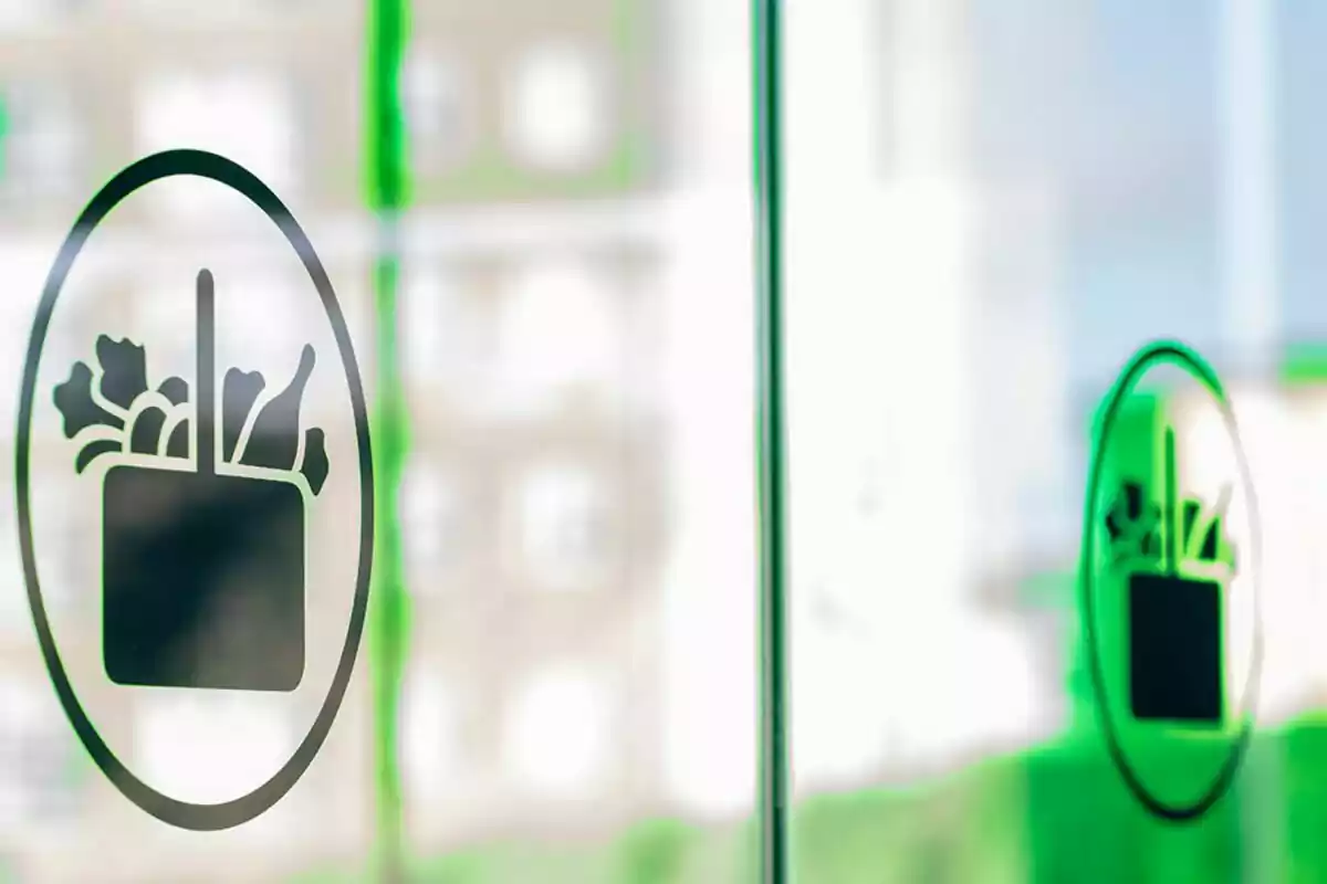 Un logotipo de una bolsa de compras con vegetales en una ventana de vidrio. Un logotipo de una bolsa de compras con vegetales en una ventana de vidrio.