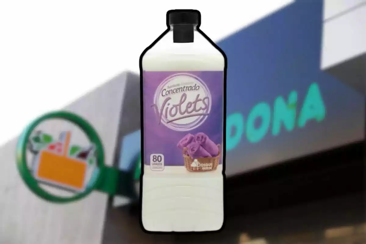Botella de suavizante concentrado con etiqueta violeta frente a un cartel de supermercado. Botella de suavizante concentrado con etiqueta violeta frente a un cartel de supermercado.