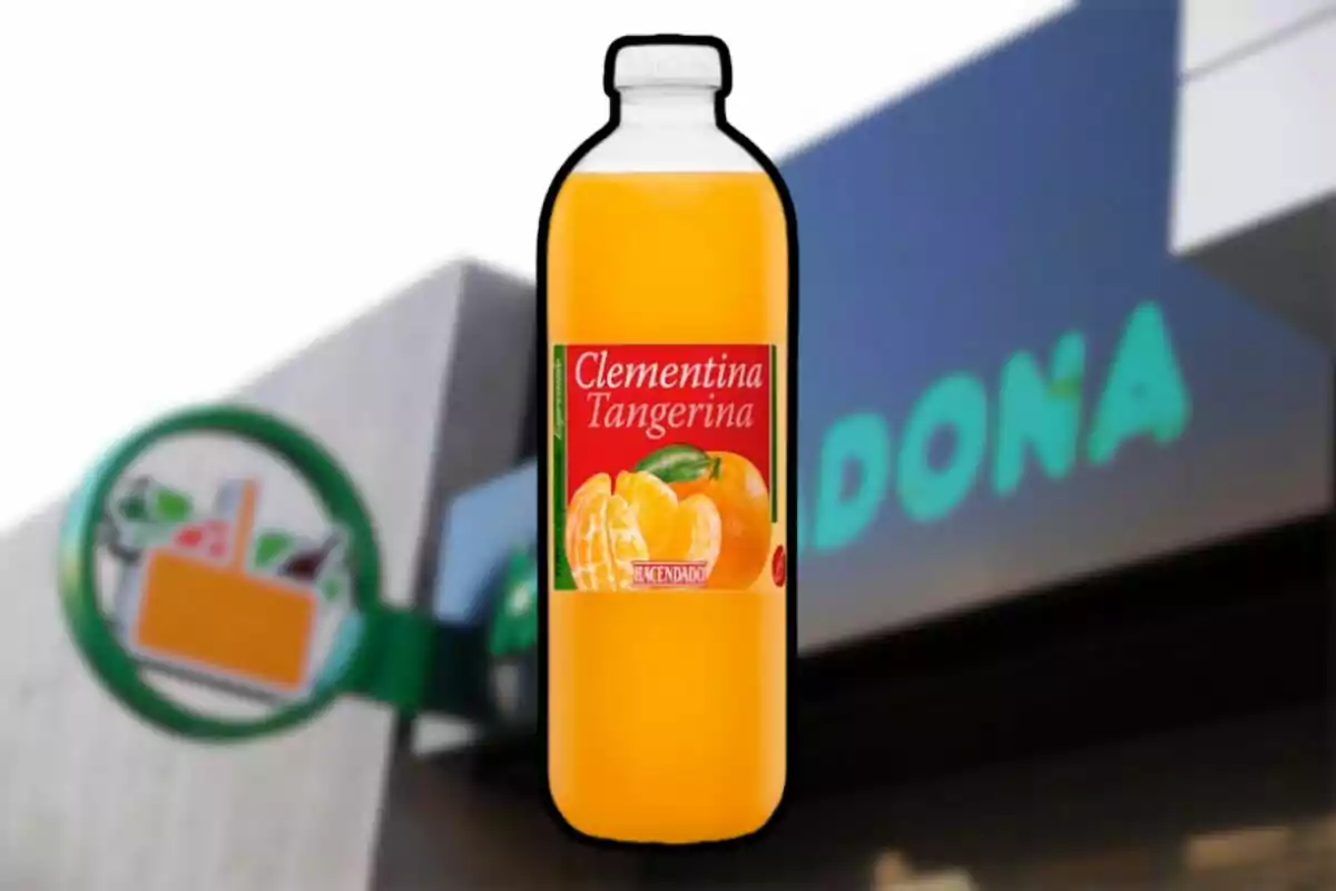 Botella de zumo de clementina y tangerina de la marca Hacendado frente a un supermercado Mercadona desenfocado Botella de zumo de clementina y tangerina de la marca Hacendado frente a un supermercado Mercadona desenfocado