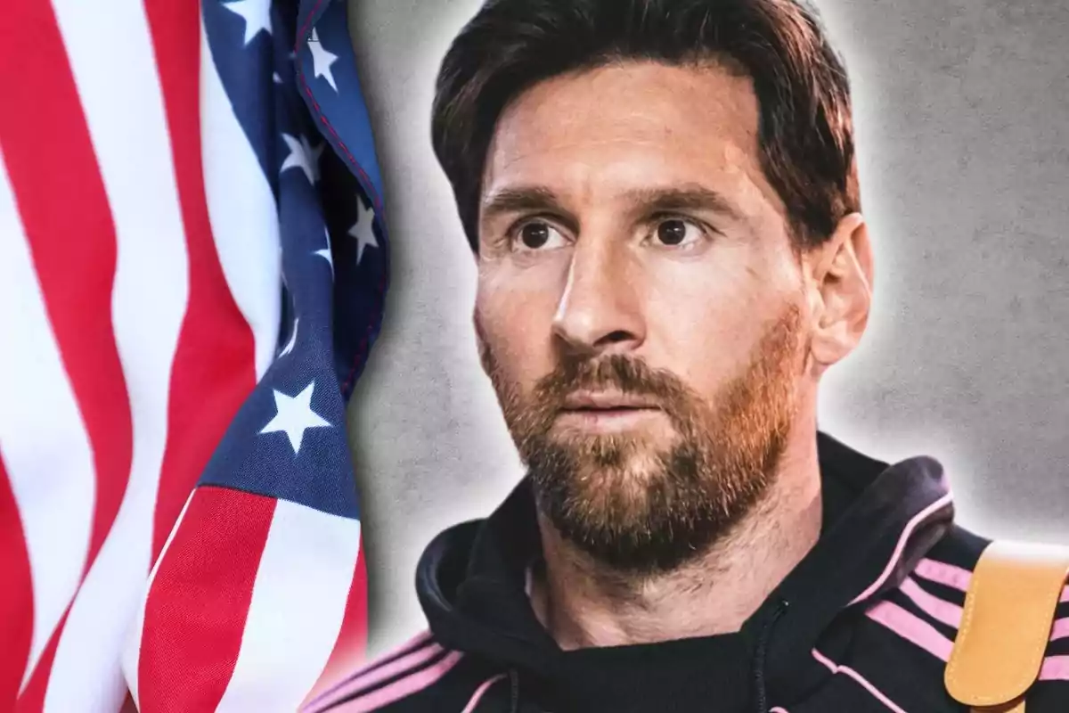 Un hombre con barba y cabello oscuro lleva una chaqueta negra con detalles rosados junto a una bandera de Estados Unidos.