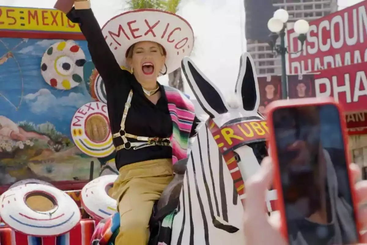 Mujer sonriente con sombrero que dice México montando un burro pintado de cebra en un ambiente festivo mientras alguien toma una foto con el celular Mujer sonriente con sombrero que dice México montando un burro pintado de cebra en un ambiente festivo mientras alguien toma una foto con el celular