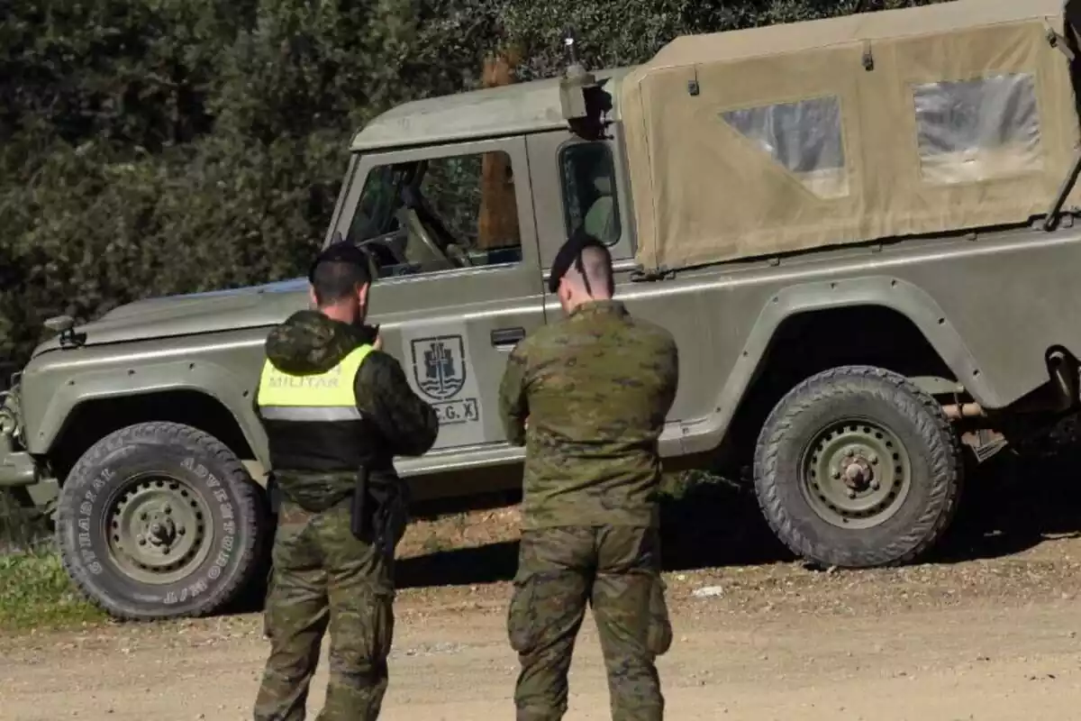 Dos militare del Ejército de España de espaldas frente a un todoterreno verde del Ejército conversando
