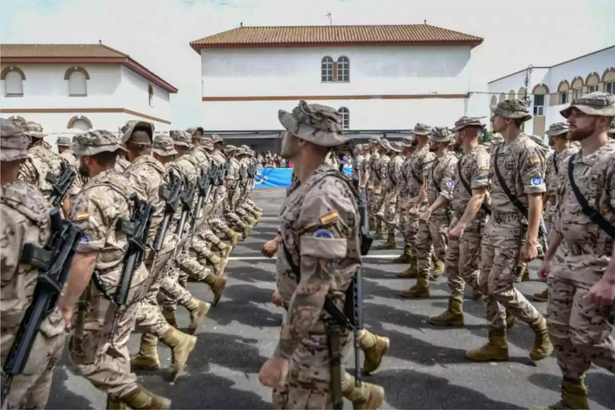 Varios militares del ejército desfilando en una calle con el uniforme oficial