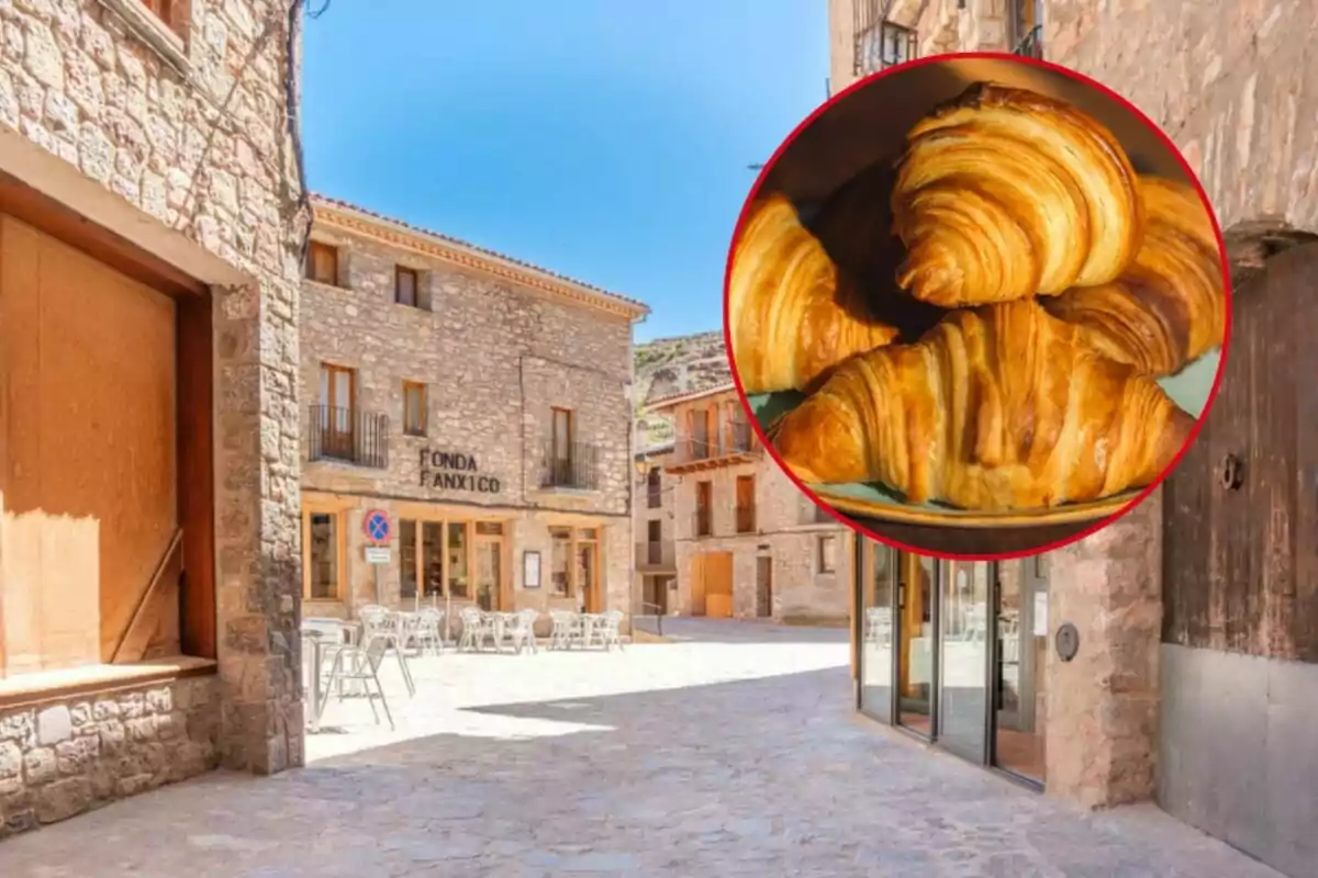 Una calle empedrada con edificios de piedra y una cafetería al fondo, con una imagen superpuesta de croissants en un círculo rojo.