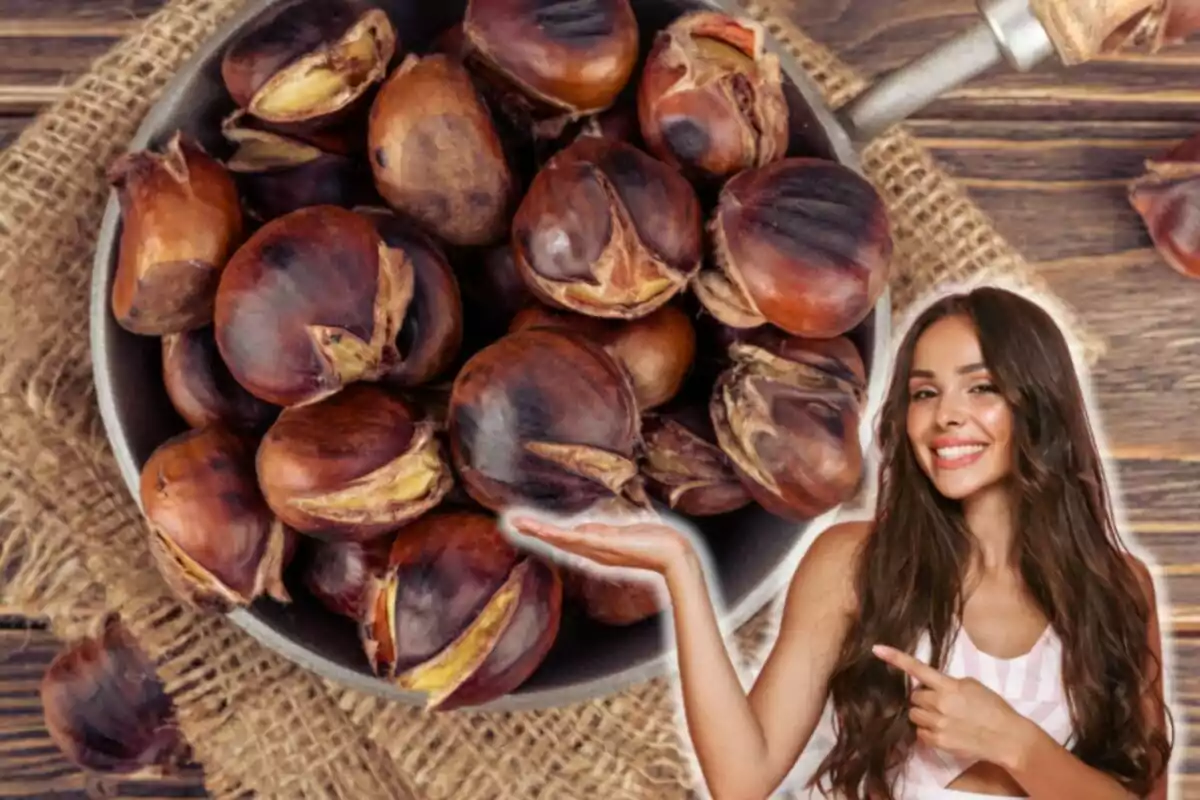 Una mujer sonriente señala un tazón lleno de castañas asadas sobre una superficie de madera con un fondo de tela de arpillera.