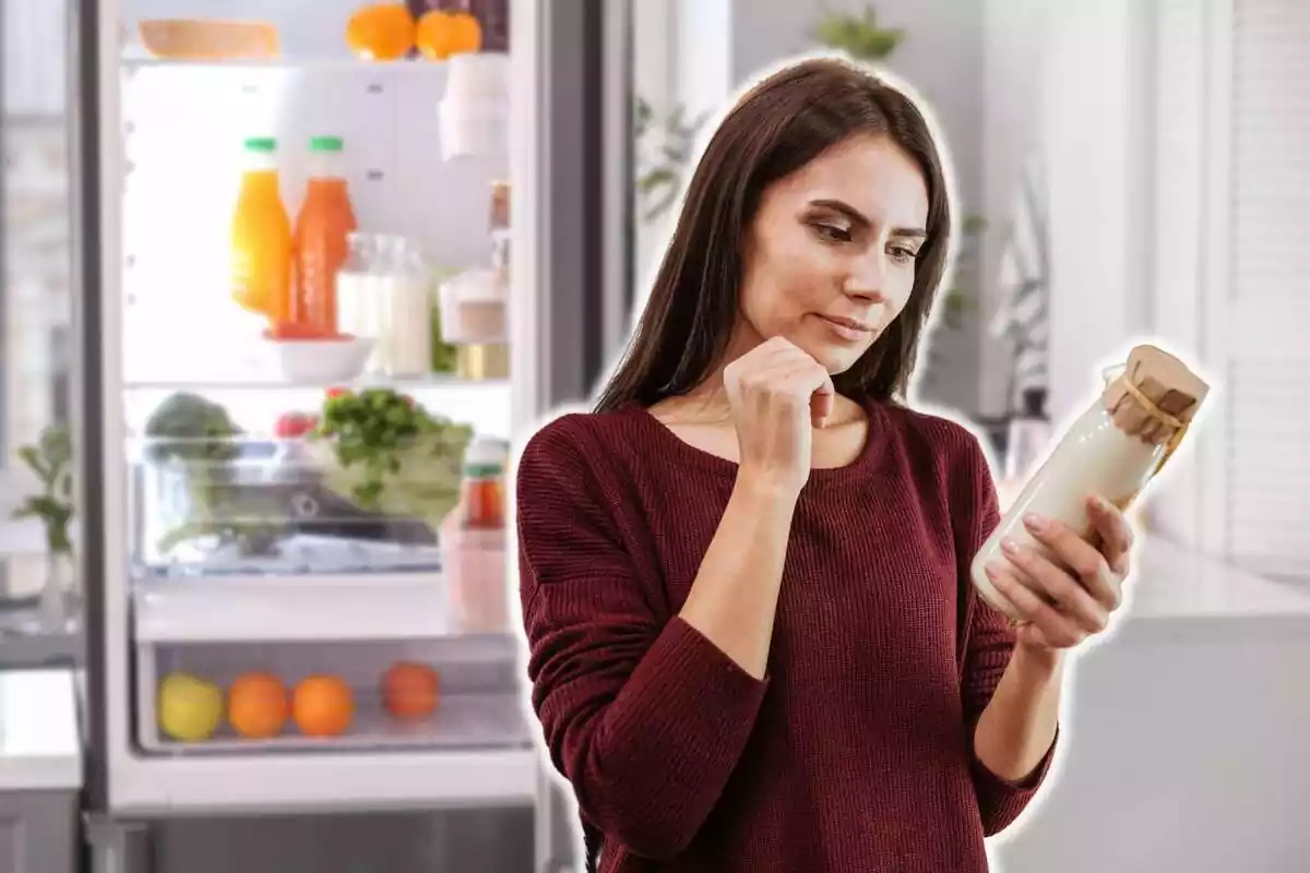 Montaje con una nevera abierta de fondo y una mujer sujetando y mirando un bote de yogur