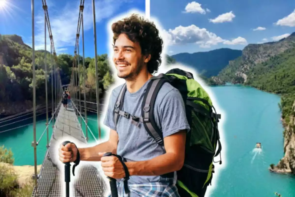Un hombre sonriente con una mochila grande y bastones de senderismo, posando frente a un paisaje natural con un puente colgante y un lago de aguas turquesas rodeado de montañas.