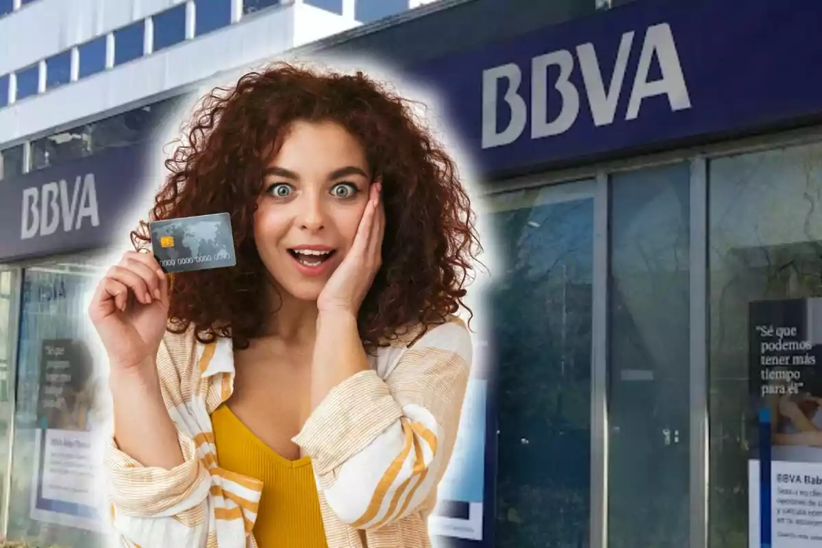 Mujer sorprendida sosteniendo una tarjeta de crédito frente a una sucursal de BBVA.