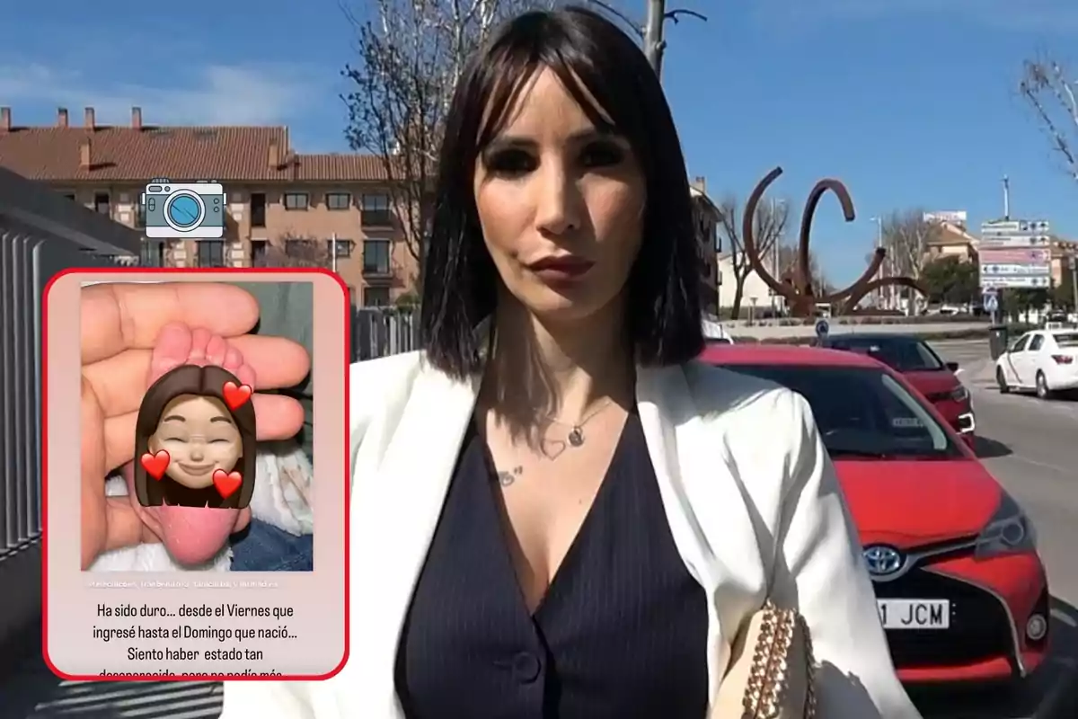 Una mujer de cabello oscuro y corto, vestida con un blazer blanco y una blusa oscura, está de pie en una calle con varios coches y edificios de fondo. En la esquina inferior izquierda de la imagen, hay una foto superpuesta de un pie de bebé sostenido por una mano, con un emoji de una cara sonriente con corazones.