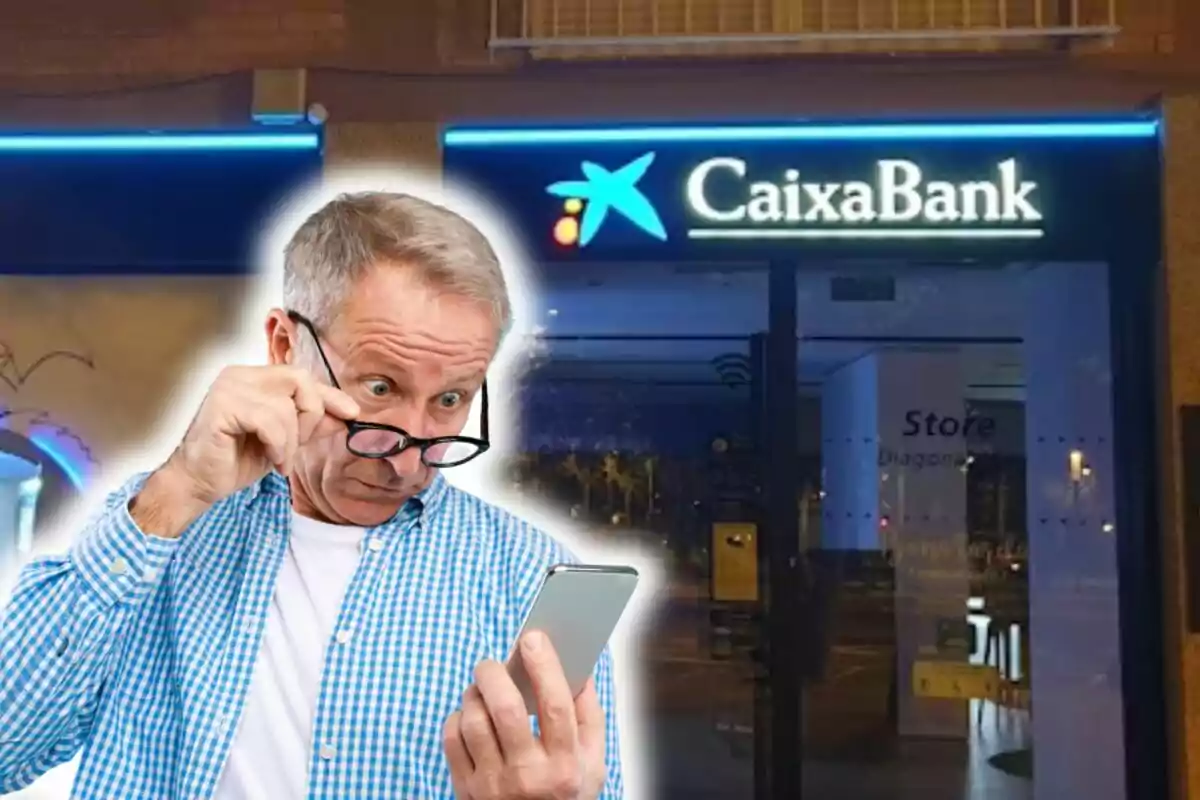 Hombre mayor mirando su teléfono móvil con expresión de sorpresa frente a una sucursal de CaixaBank.