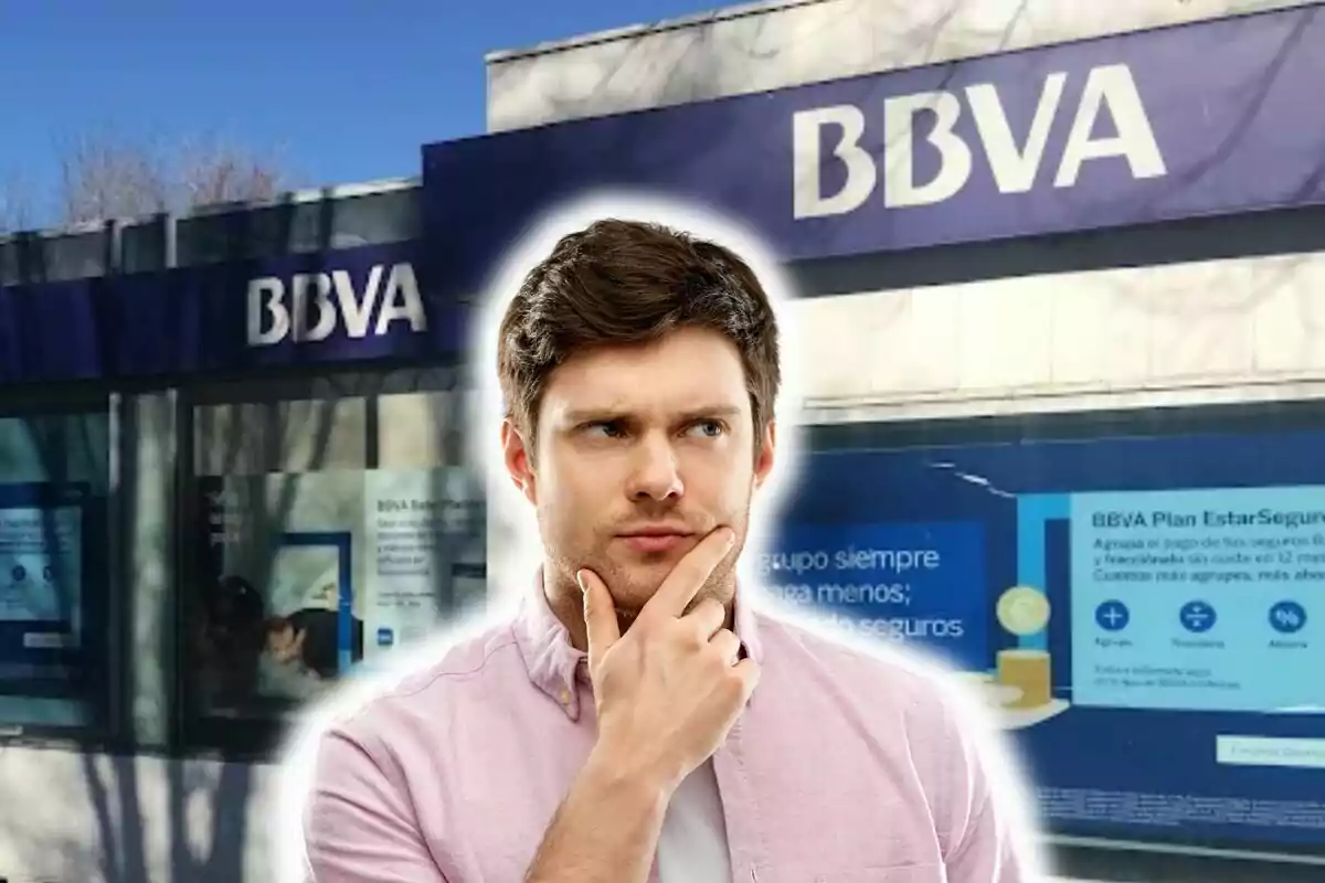 Un hombre pensativo frente a una sucursal del banco BBVA.