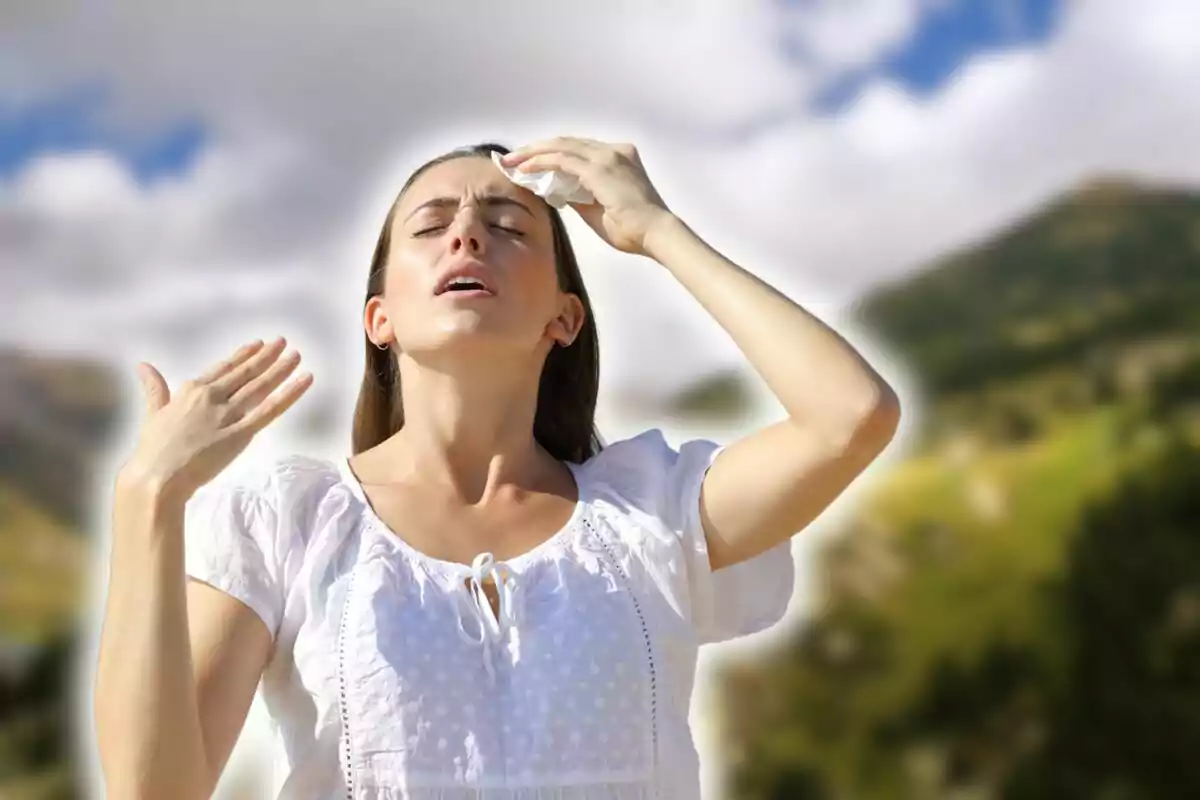 Persona con camisa blanca secándose el sudor de la frente en un día soleado al aire libre.