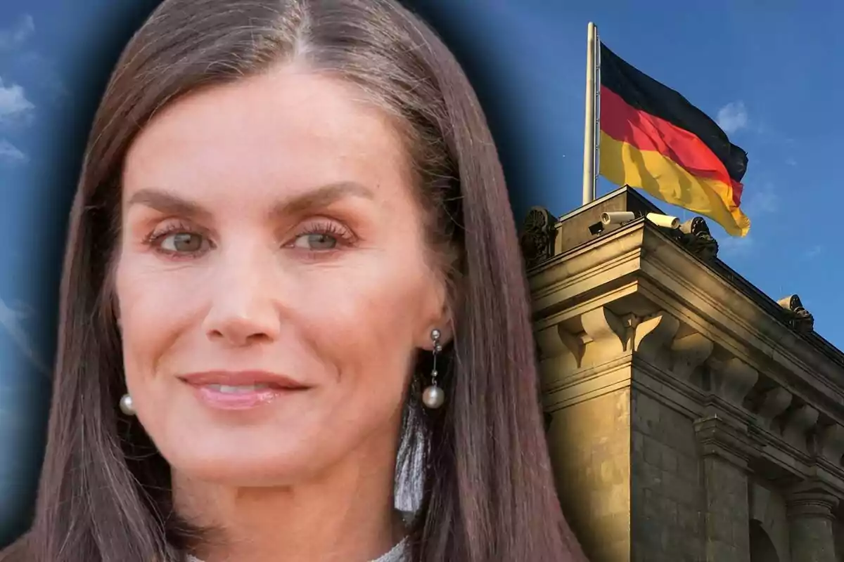 Primer plano de Letizia Ortiz con pendientes de perla junto a un edificio con una bandera de Alemania ondeando en lo alto.