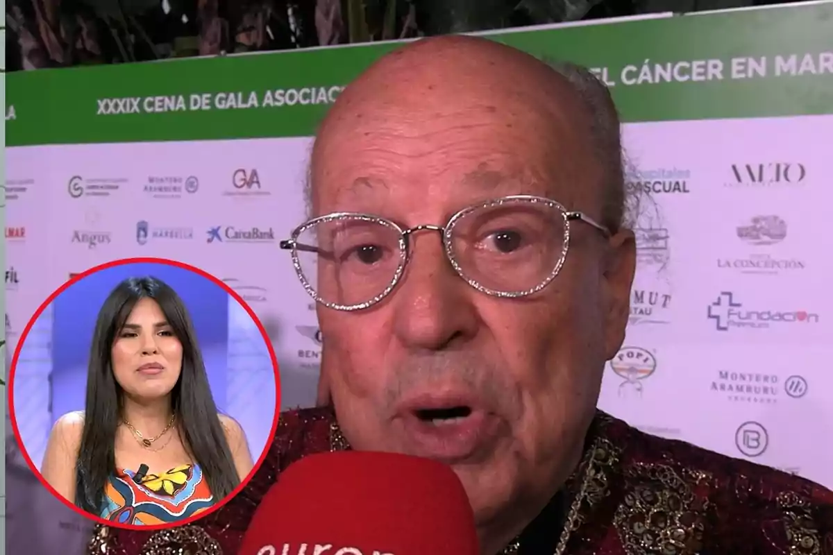 Un hombre mayor con gafas y un micrófono rojo en un evento de gala con un fondo de logotipos y un recuadro que muestra a una mujer joven.