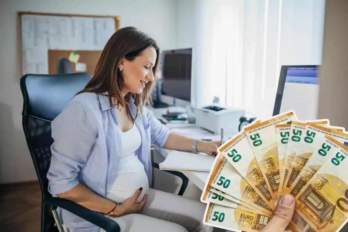 Una mujer embarazada trabajando en una oficina, y billetes de 50 euros a la derecha