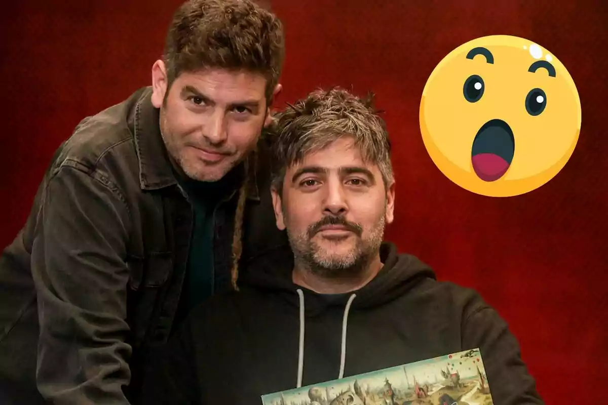 Dos personas posan juntas frente a un fondo rojo con un emoji sorprendido al lado.