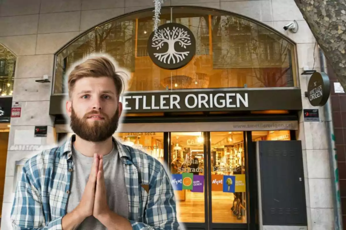 Hombre con barba y camisa a cuadros en posición de oración frente a la entrada de una tienda llamada Ametller Origen.