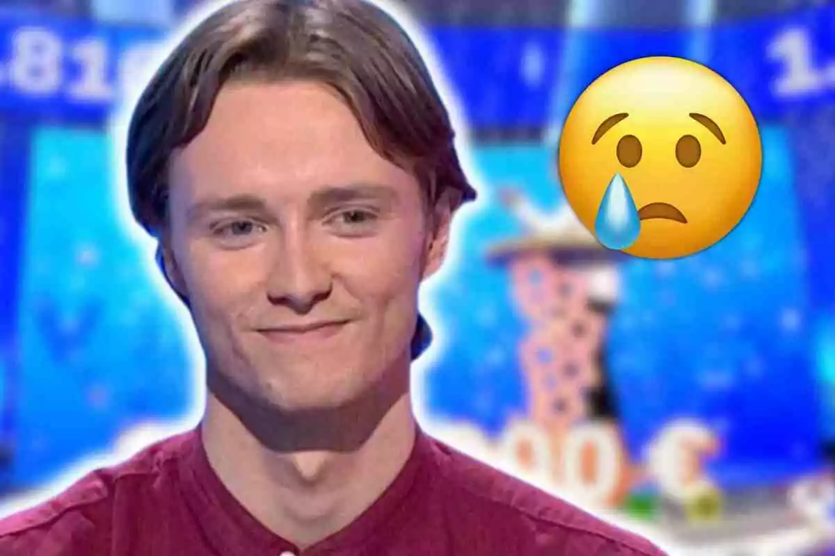Manu con camisa roja sonríe levemente en 'Pasapalabra' con un emoji de carita triste y lágrima sobre un fondo azul desenfocado
