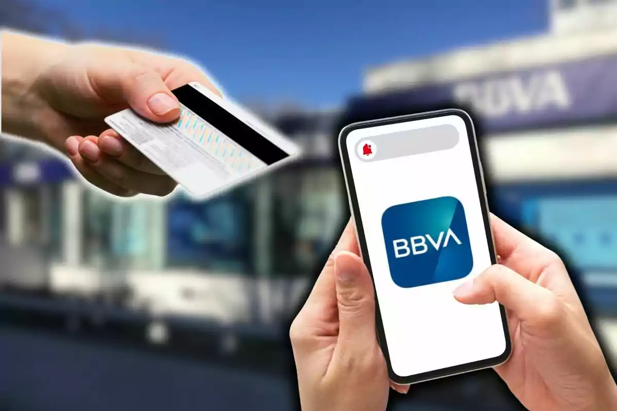 Mano sosteniendo una tarjeta de crédito y otra mano sosteniendo un teléfono móvil con el logo de BBVA en la pantalla frente a un fondo borroso de un edificio.