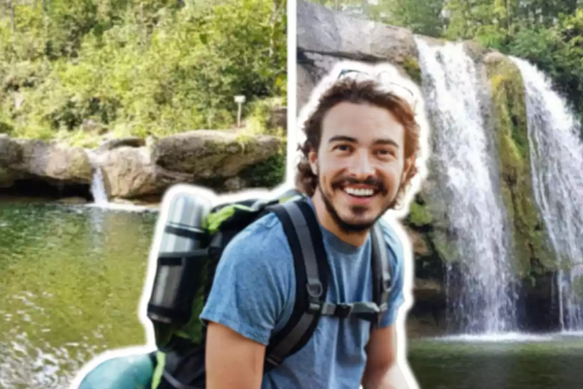 Un hombre sonriente con mochila frente a una cascada y un río rodeado de vegetación.