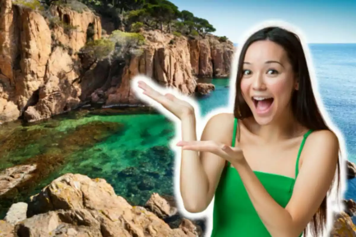 Una mujer sonriente con un vestido verde señala con ambas manos hacia un paisaje costero con acantilados rocosos y agua turquesa.