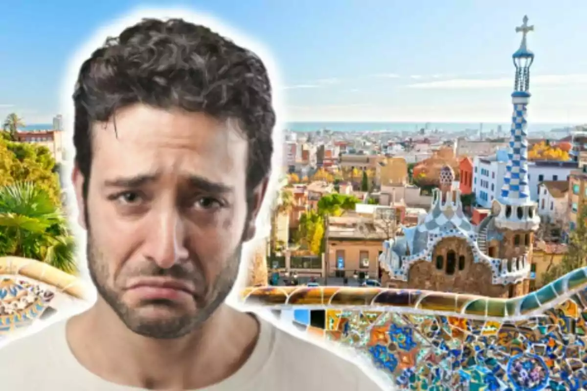 Un hombre con expresión triste frente a un paisaje urbano con arquitectura colorida que pertenece al Park Güell y un cielo despejado.