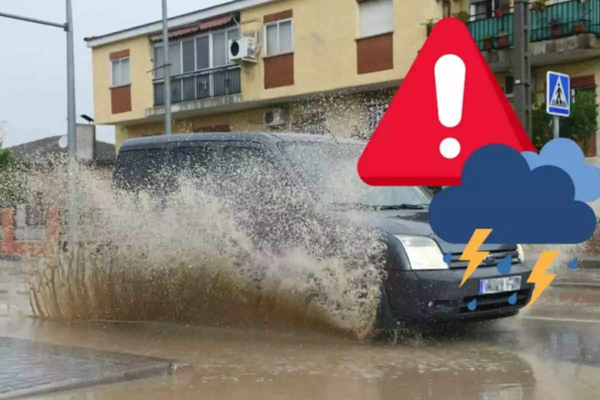 Un coche negro salpicando agua mientras pasa por un charco grande en una calle residencial durante una tormenta.