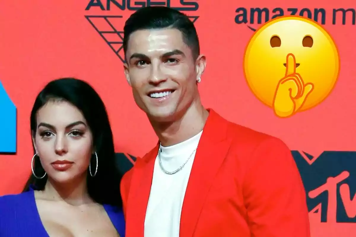 Georgina Rodríguez y Cristiano Ronaldo posando en un evento con un fondo rojo y un emoji de silencio.