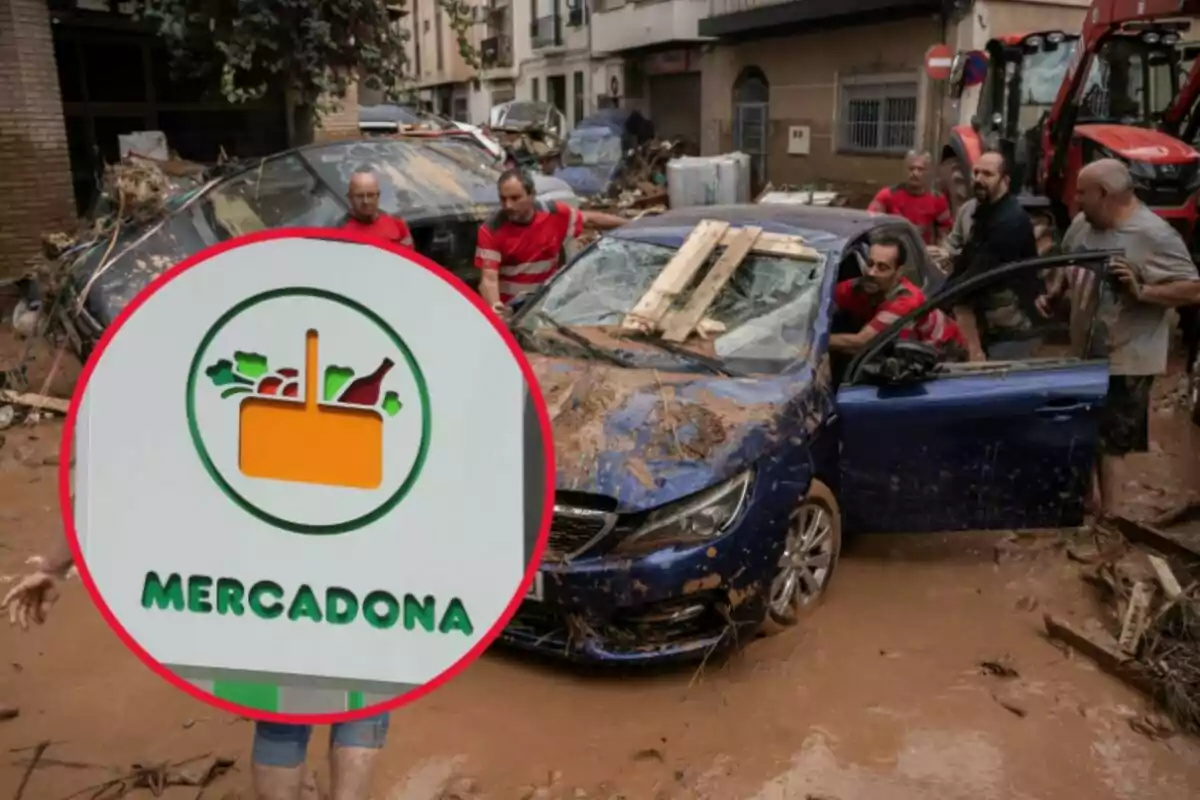 Personas trabajando para rescatar un coche cubierto de barro tras una inundación en una calle, con un cartel de Mercadona en primer plano.