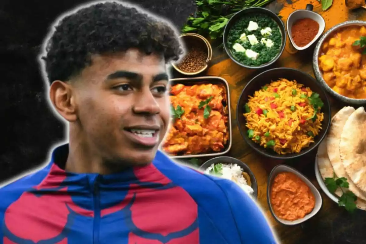 Un joven con una camiseta azul y roja está sonriendo frente a una mesa llena de platos de comida variada, incluyendo arroz, curry y pan.