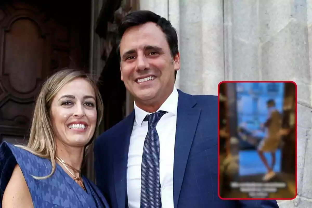 María Amores e Ion Aramendi sonriente vestida formalmente, con Ion usando un traje azul y María con un vestido azul, posando frente a una puerta de madera tallada y una pared de piedra.