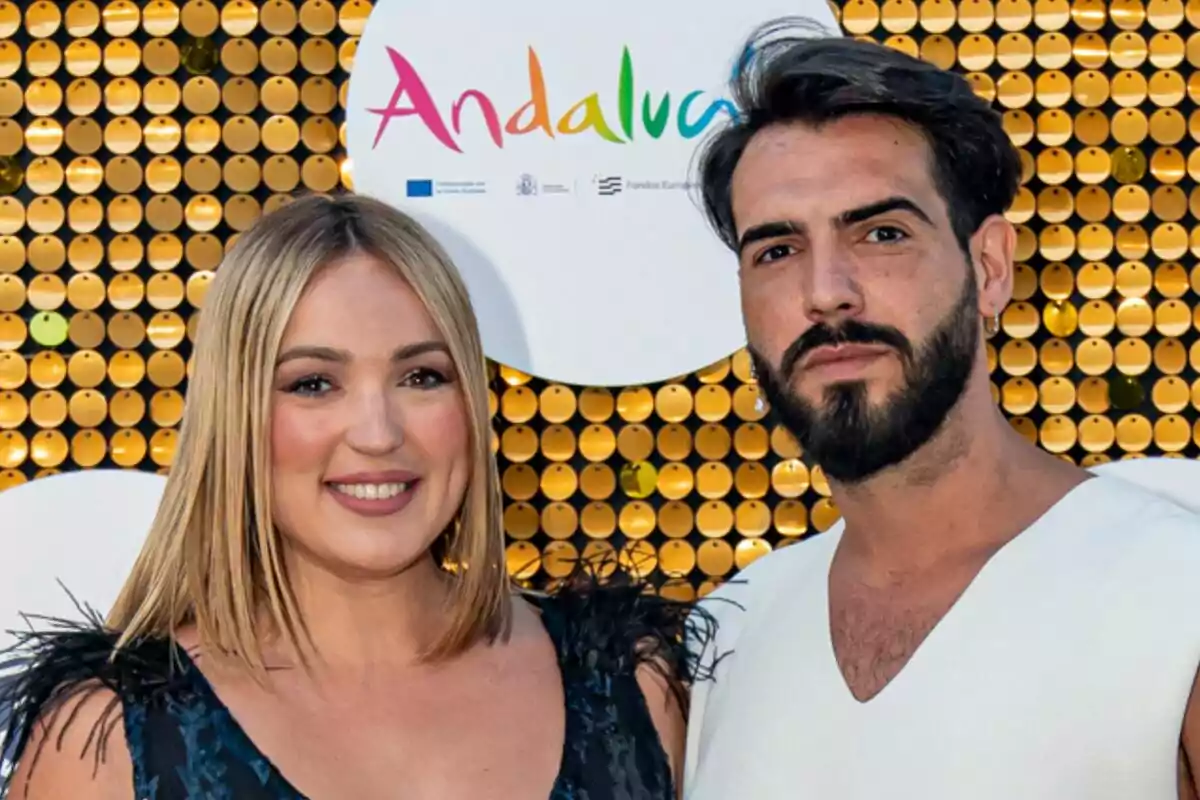 Marta Riesco y Alejandro Caraza posan juntos frente a un fondo decorativo con el logotipo de Andalucía.