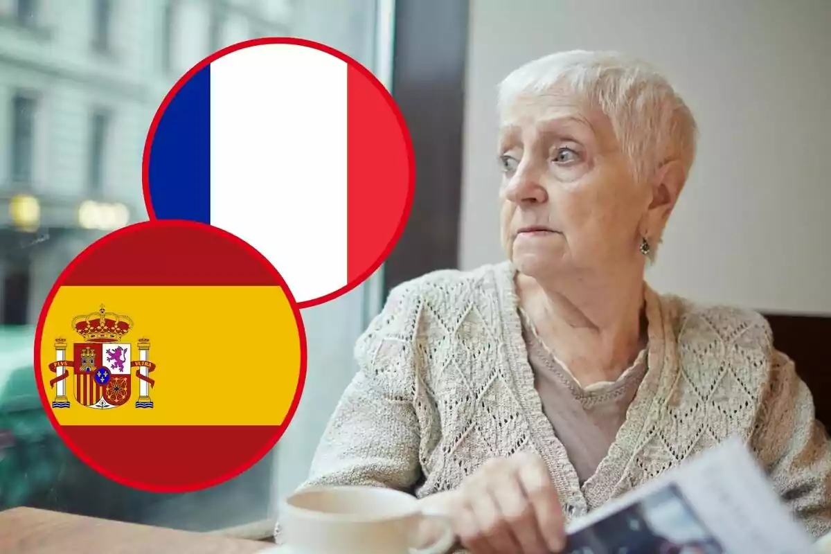 Mujer mayor sentada junto a una ventana con las banderas de Francia y España superpuestas en la imagen.