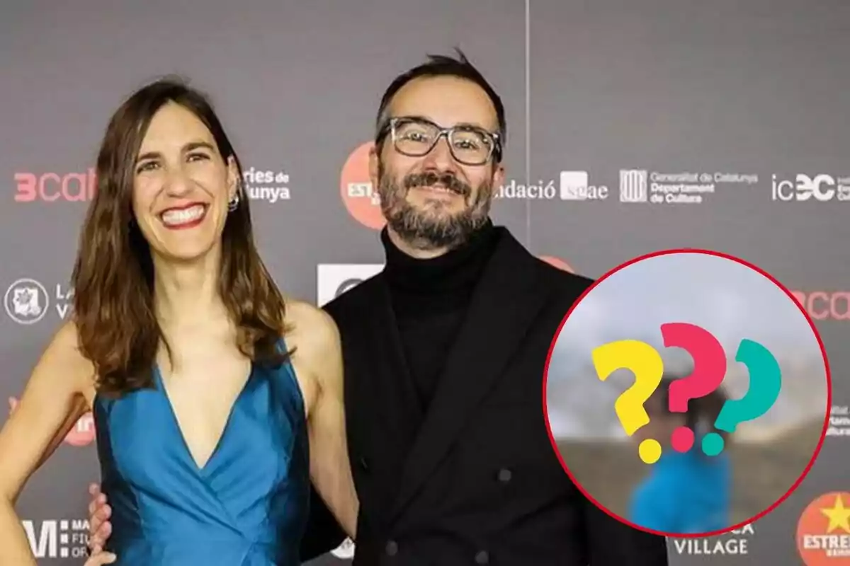 Neus Rossell con un vestido azul y Jair Domínguez con gafas y barba posan juntos en un evento con un fondo de logotipos.