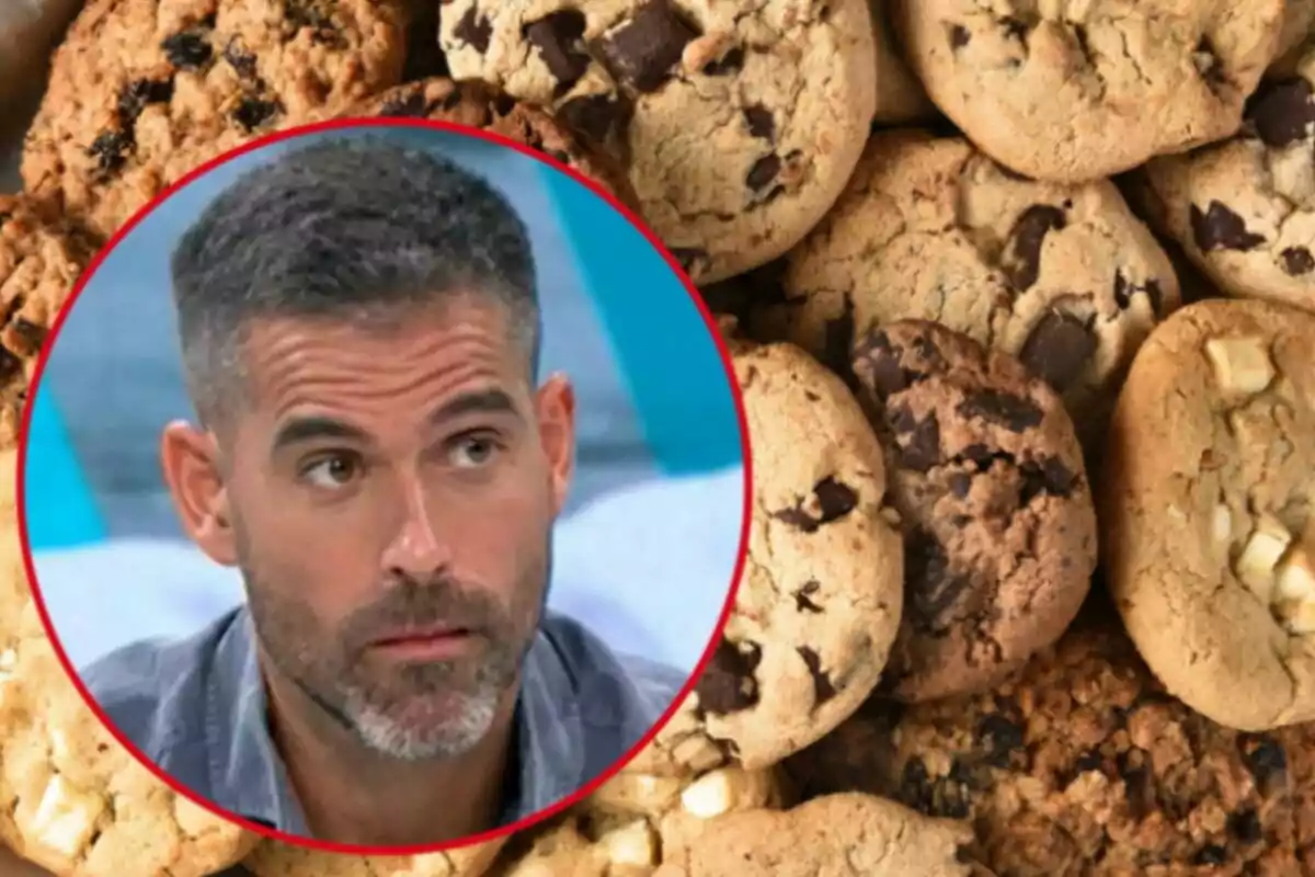 Un hombre con barba y cabello corto dentro de un círculo rojo sobre un fondo de galletas con chispas de chocolate.