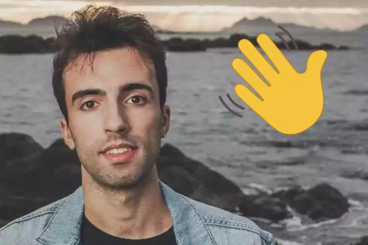 Bruno Vila con chaqueta de mezclilla frente a un paisaje costero con un emoji de mano saludando superpuesto.