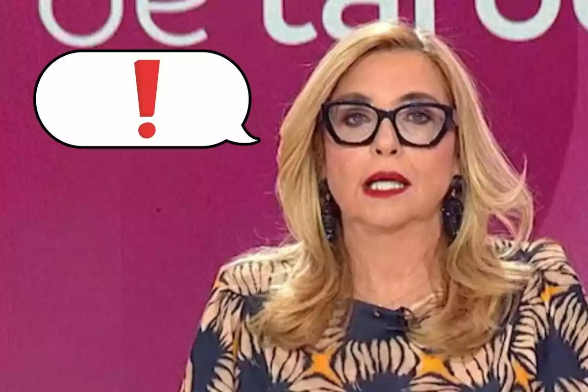 Inmaculada Casal con gafas y cabello rubio en un programa de televisión, con un globo de diálogo que contiene un signo de exclamación rojo.