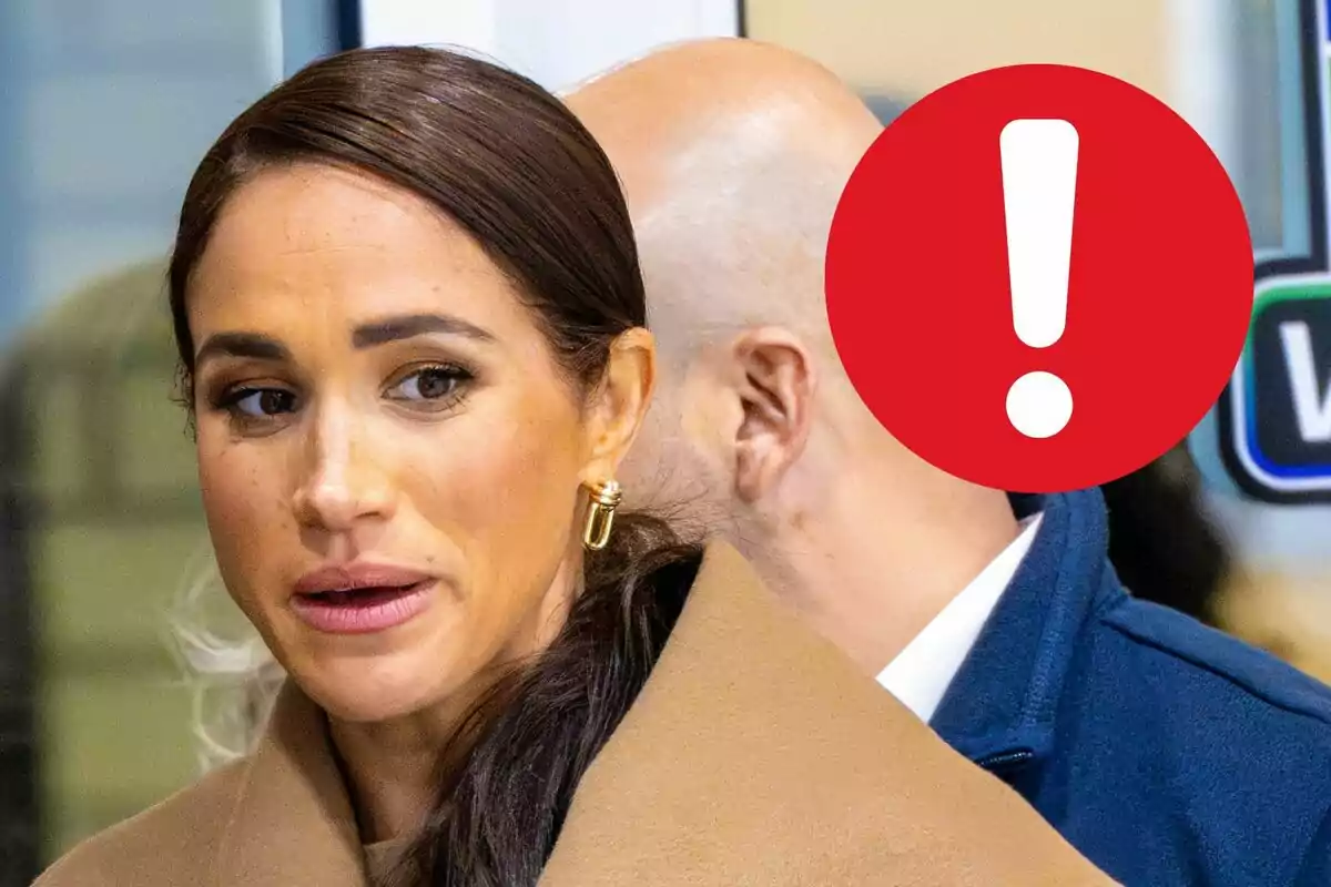 Meghan Markle con cabello oscuro y abrigo beige está en un lugar público, mientras un círculo rojo con un signo de exclamación cubre parcialmente a otra persona en el fondo.