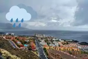 Montaje de un pueblo costero con nubes encima del mar y un icono de nubes con lluvia