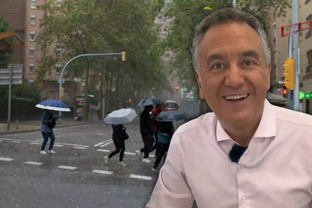 Una persona sonriente en primer plano con un fondo de personas cruzando la calle bajo la lluvia con paraguas.