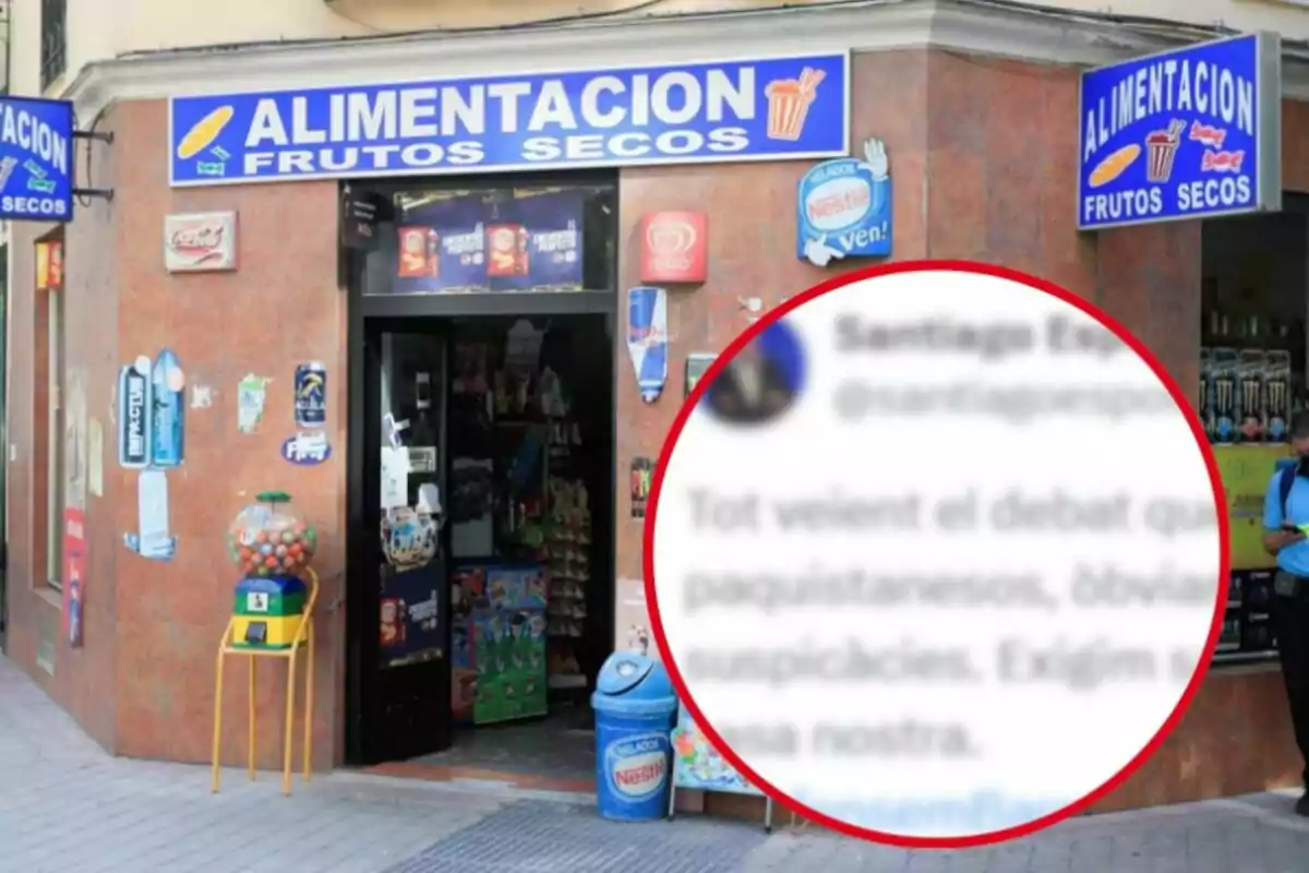 Una tienda de alimentación y frutos secos con letreros azules y un hombre de pie usando su teléfono móvil.