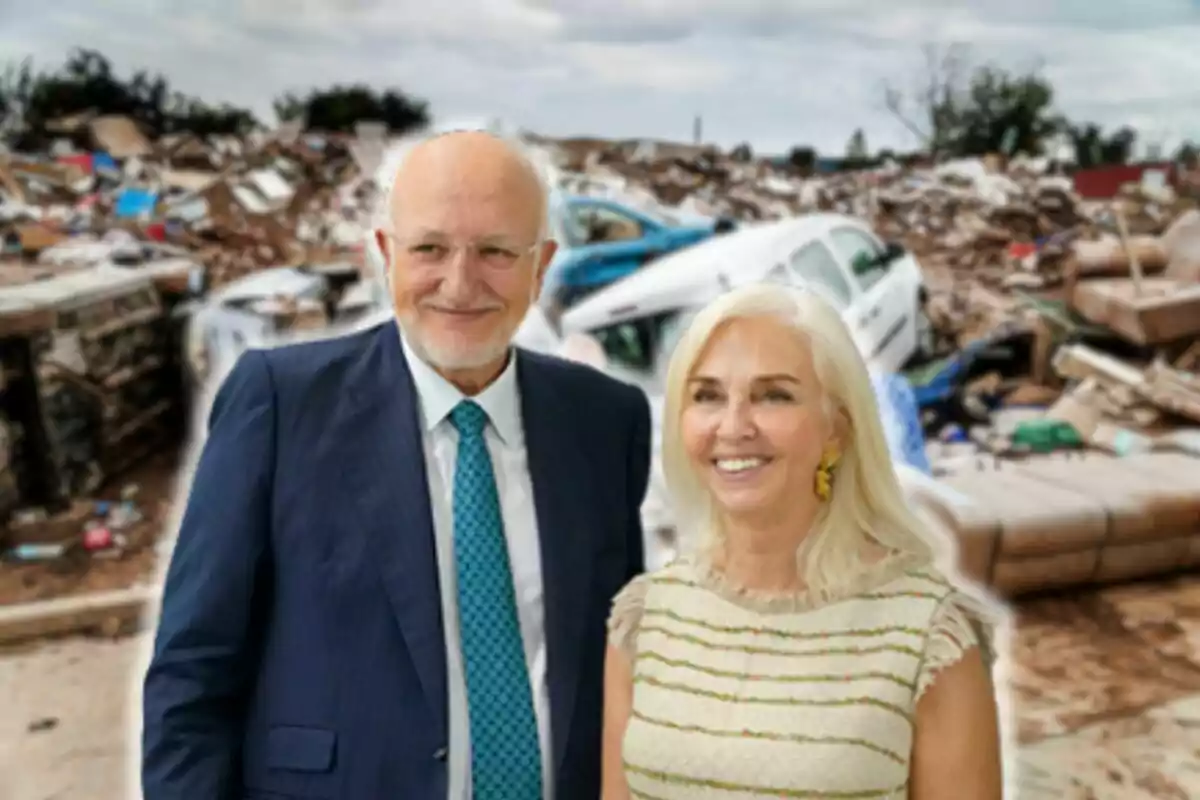 Juan Roig y Hortensia Herrero sonriente posa frente a un fondo de escombros y vehículos dañados.